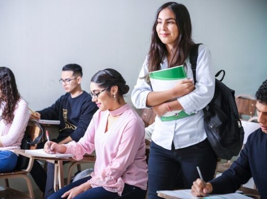 Leerlingen werken in een klas terwijl een student met boeken binnenkomt