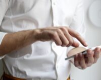 Persoon in wit overhemd gebruikt een smartphone voor korte leermomenten