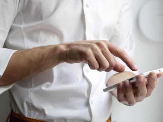Persoon in wit overhemd gebruikt een smartphone voor korte leermomenten